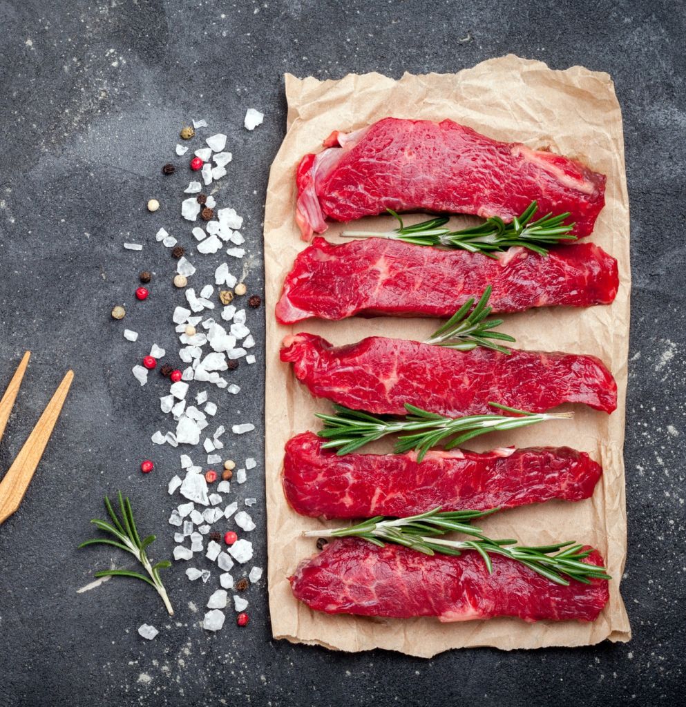 Raw meat on dark background. Raw beef stroganoff with herbs and spices. Cooking meat